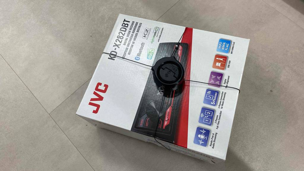 Im Test: Auf einem Fließenboden liegt ein DAB-Autoradio von JVC.