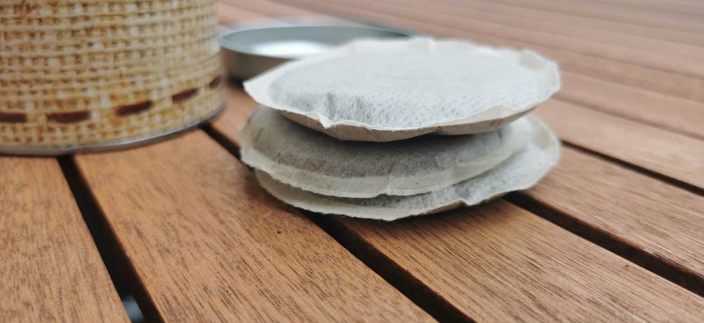 Kaffeepads getestet: Gestapelte Pads von der Seite auf einem Holztisch.