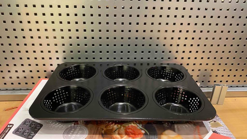 Im Test: Eine Brötchen-Backform von der Seite vor einer hellen Lochwand.