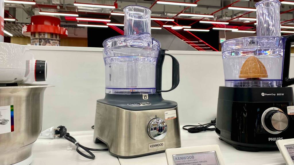 Kompakt-Küchenmaschine im Test: eine Kompakt-Küchenmaschine von vorn ersichtlich, welche in einem Regal neben anderen Modellen steht.