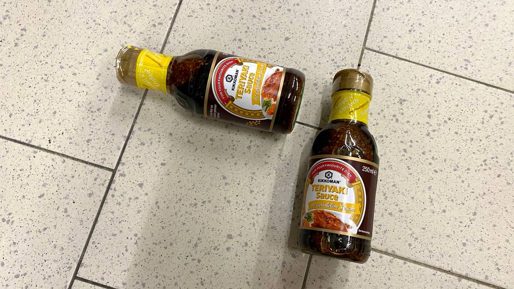 Teriyaki-Sauce getestet: Zwei Flaschen Sauce liegen nebeneinander auf Fließenboden
