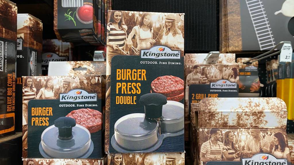 Mehrere getestete Burgerpressen stehen nebeneinander im Regal.