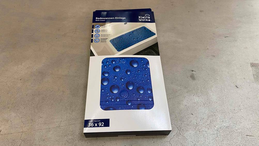 Badewannenmatte im Test: Eine Originalverpackung auf einem Steinboden