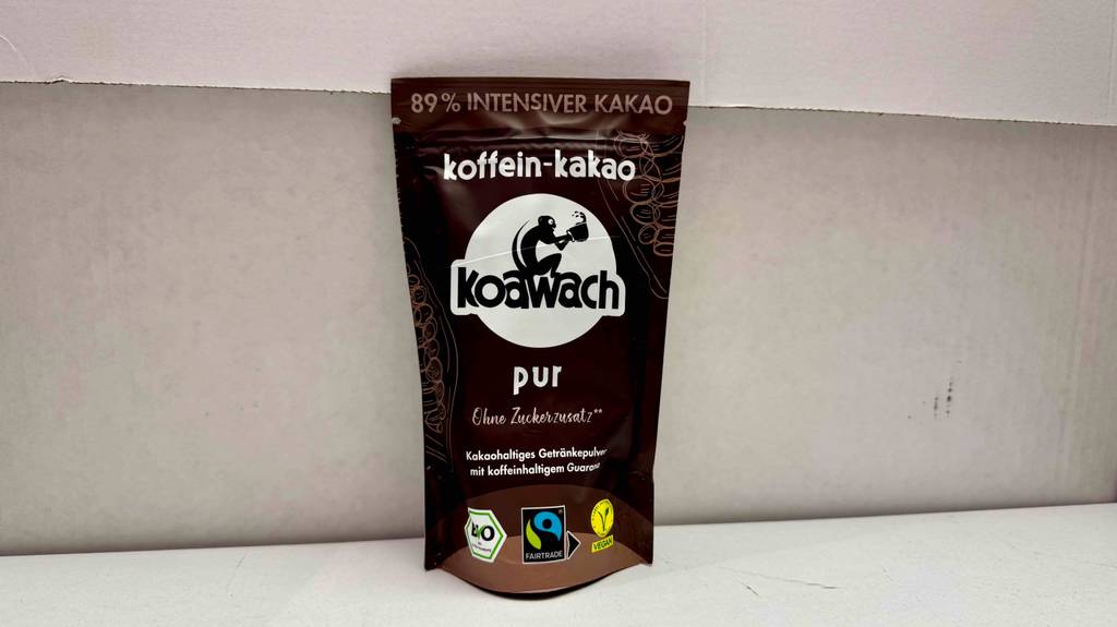Das getestete Kakaopulver ohne Zucker befindet sich in einer wiederverschließbaren braunen Kunststofftüte vor einer hellen Wand.
