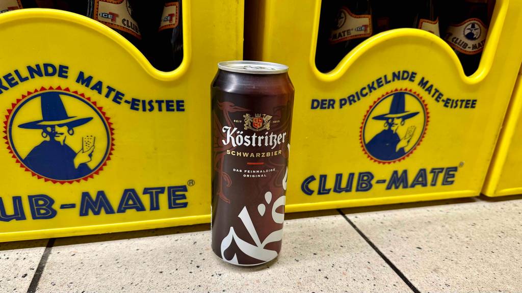 Test: Eine Dose Schwarzbier steht vor gelben Getränkekisten.