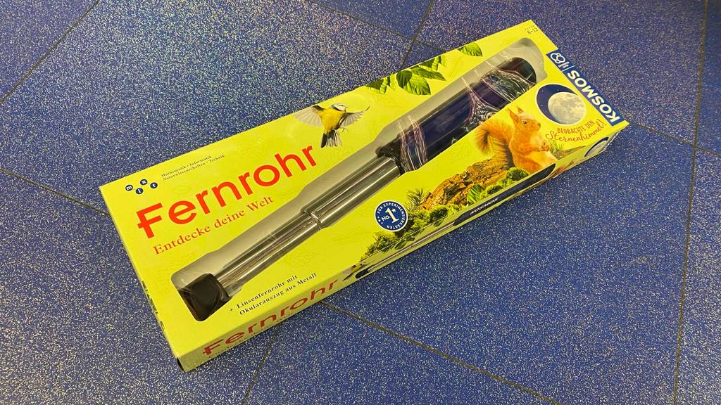 Auf einem blauen Boden liegt ein getestetes Fernrohr (Kinder) verpackt.