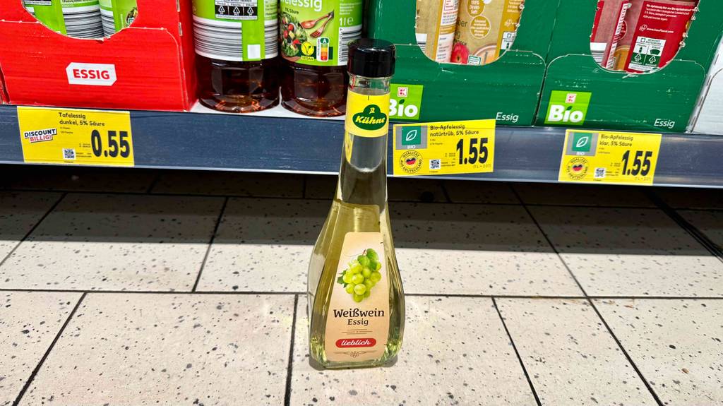 Getesteter Weißweinessig steht vor einem Regal.