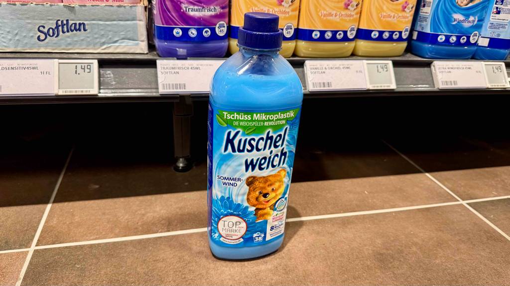 Der getestete Kuschelweich-Weichspüler in der Duftrichtung Sommerwind steht vor einem Regal.