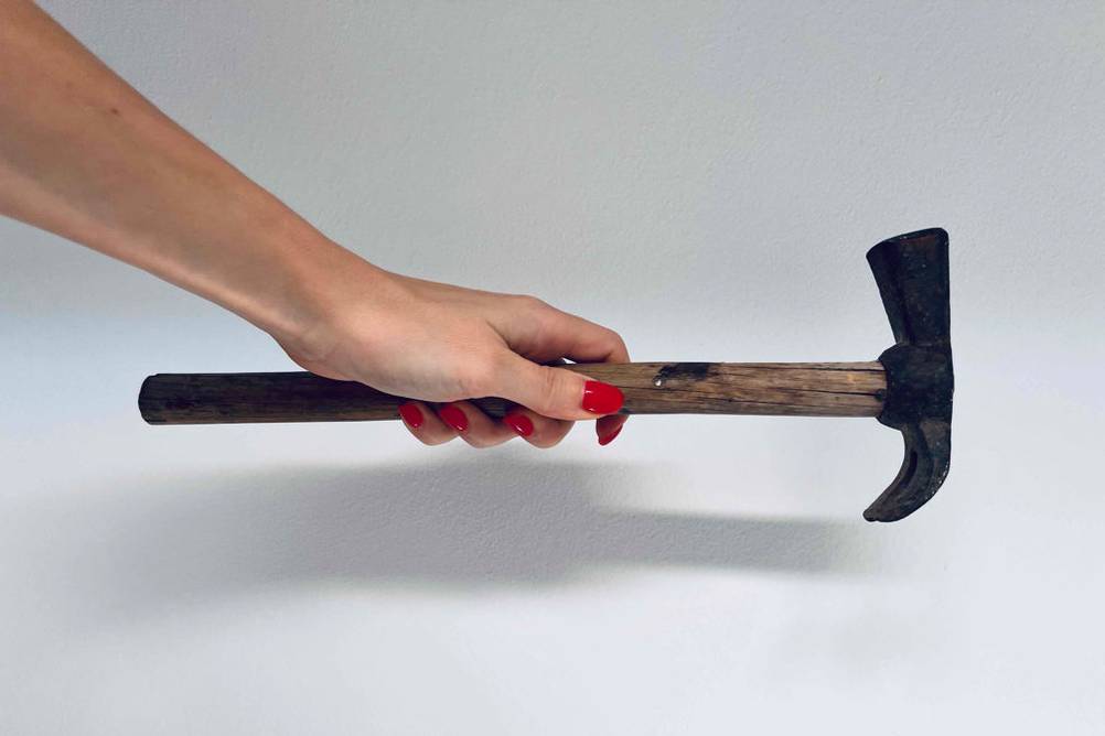 Latthammer im Test: Eine Hand hält einen Hammer am Stiel vor eine weiße Wand