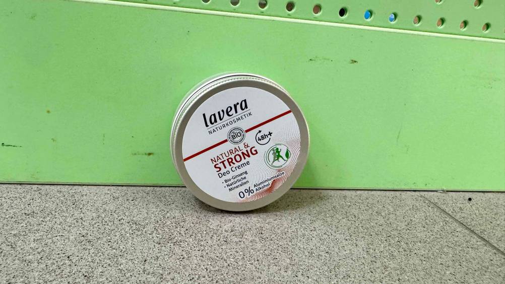 Das getestete Deo ohne Aluminium und Alkohol lehnt an einer grünen Wand.