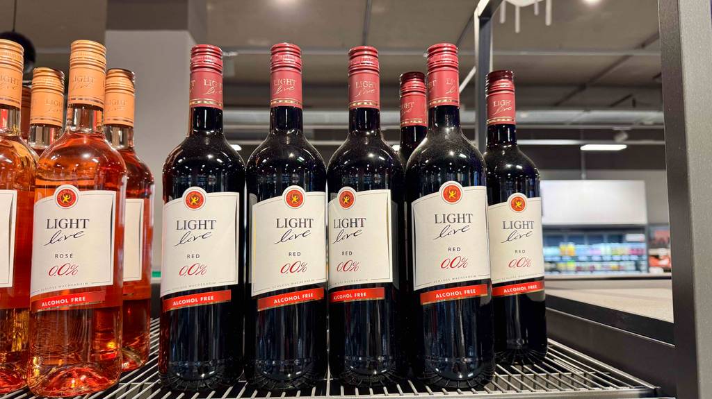 Mehrere Flaschen des getesteten alkoholfreien Rotweins stehen nebeneinander in einem Regal, worin sich auch der alkoholfreie Weißwein befindet.