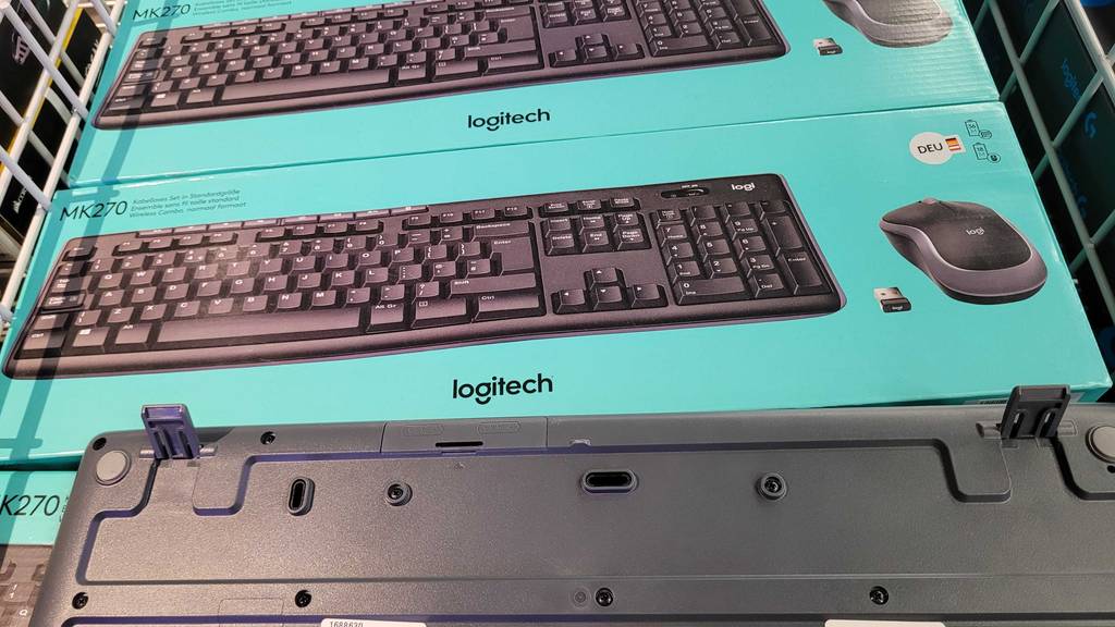Rückseite einer getesteten Funktastatur, die vor den Verpackungen patziert ist.