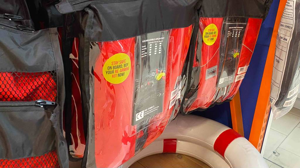 Rettungsweste im Test: Rettungswesten in Verpackung hängen in einem Regal.