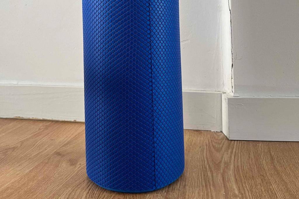 Massageroller im Test: Eine blaue Massagerolle steht auf einem Holzboden vor heller Wand