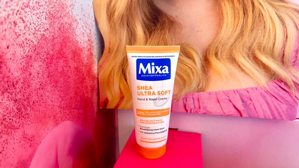 Eine getestete Mixa-Handcreme für sehr trockene Haut steht auf einer roten Fläche. 