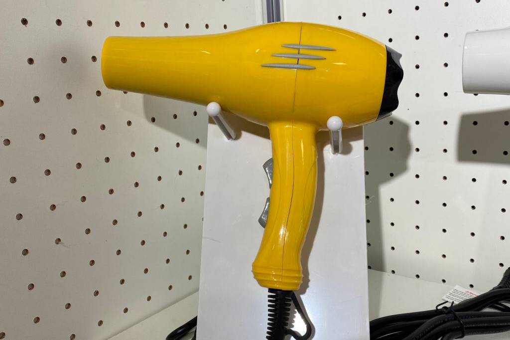 Profi Haartrockner im Test: Ein gelber Haartrockner in einer Halterung in einem Regal