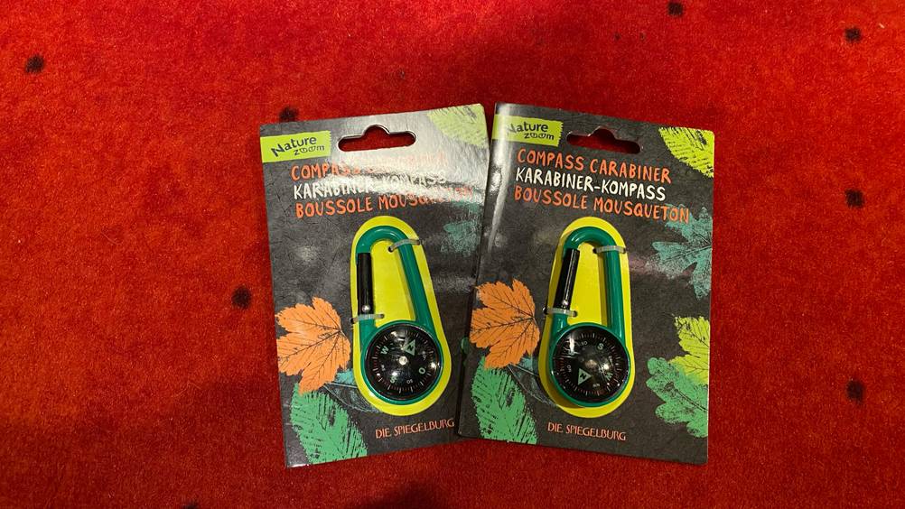Im Test: Zwei verpackte Kompass leicht übereinander auf einer roten Fläche.