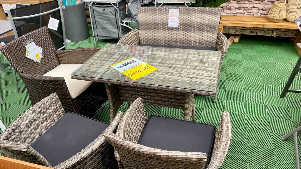 Lounge-Möbel-Set im Test: einLounge-Möbel-Set bestehend aus drei Sesseln, einem Tisch und einer Bank mit Schilder darauf befestigt, in einem Geschäft ausgestellt.