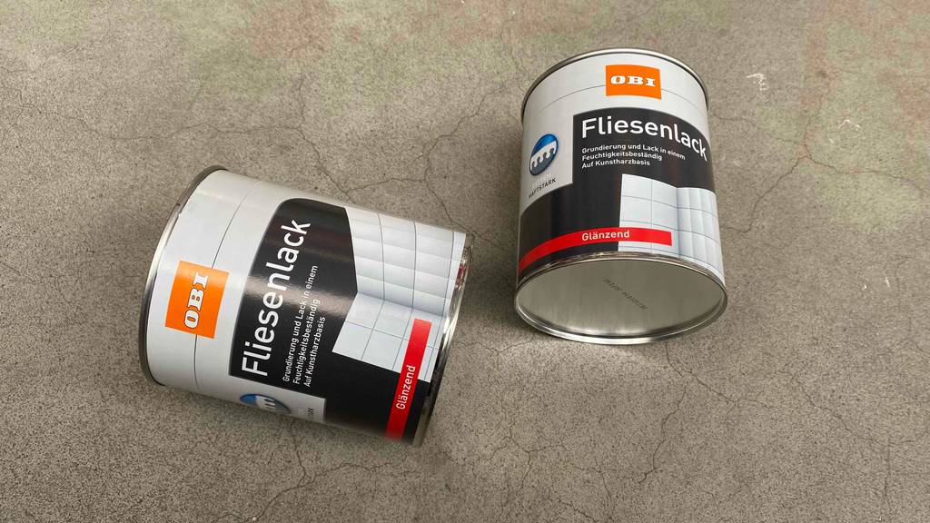 Fliesenlack im Test: Zwei Fliesenlacke auf einem Boden liegend mit glänzendem Finish.