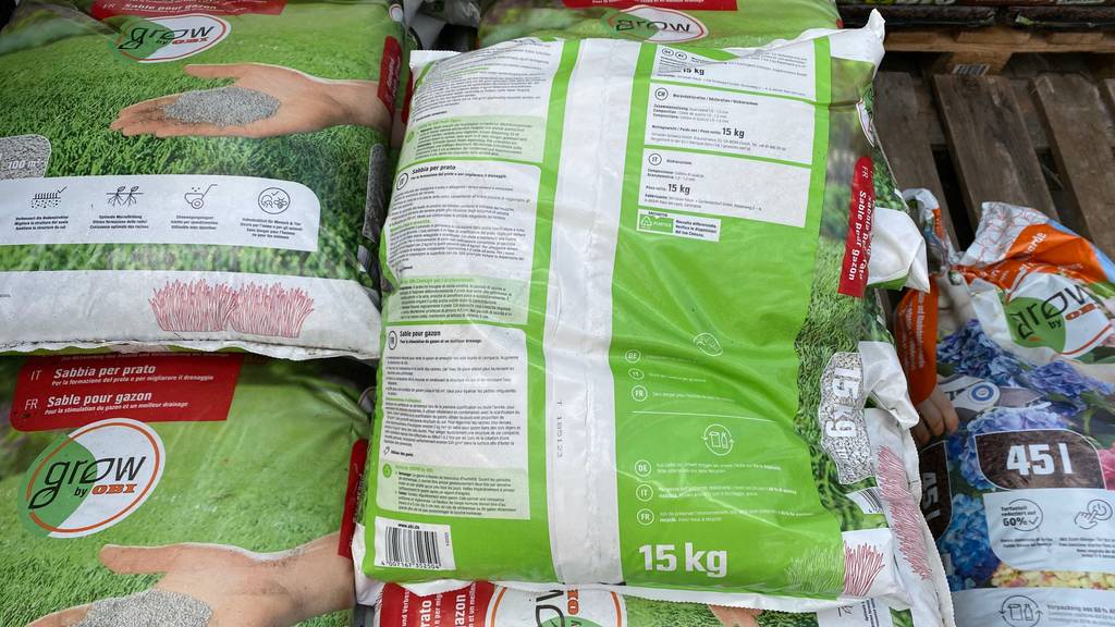 Im Test: Eine Packung Rasenerde liegt mit der Rückseite nach oben auf mehreren anderen Packungen