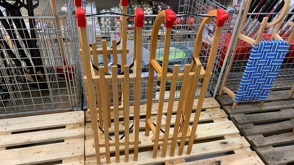 Schlitten im Test: zwei Holzschlitten aufrecht stehend auf einer Palette in einem Geschäft.