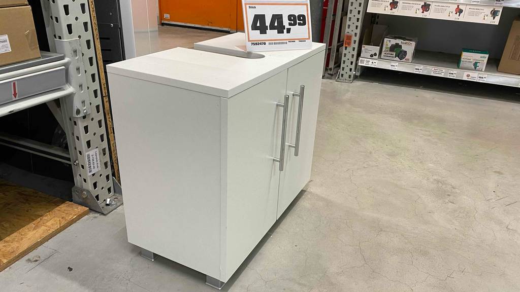 Waschbeckenunterschrank-Test: Ein Waschbeckenunterschrank in der Farbe Weiß mit geschlosseen Türen und Preisschild darauf in einem Geschöft stehend.