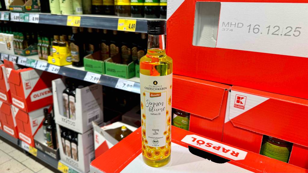 Eine getestete Flasche Sonnenblumenöl steht vor einem Regal auf Kartons.
