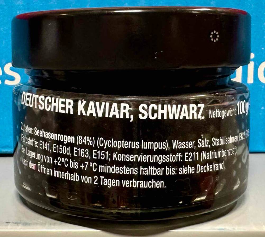 Der schwarze, deutsche getestete Kaviar in der 100-g-Glasdose steht vor einem blauen Hintergrund.