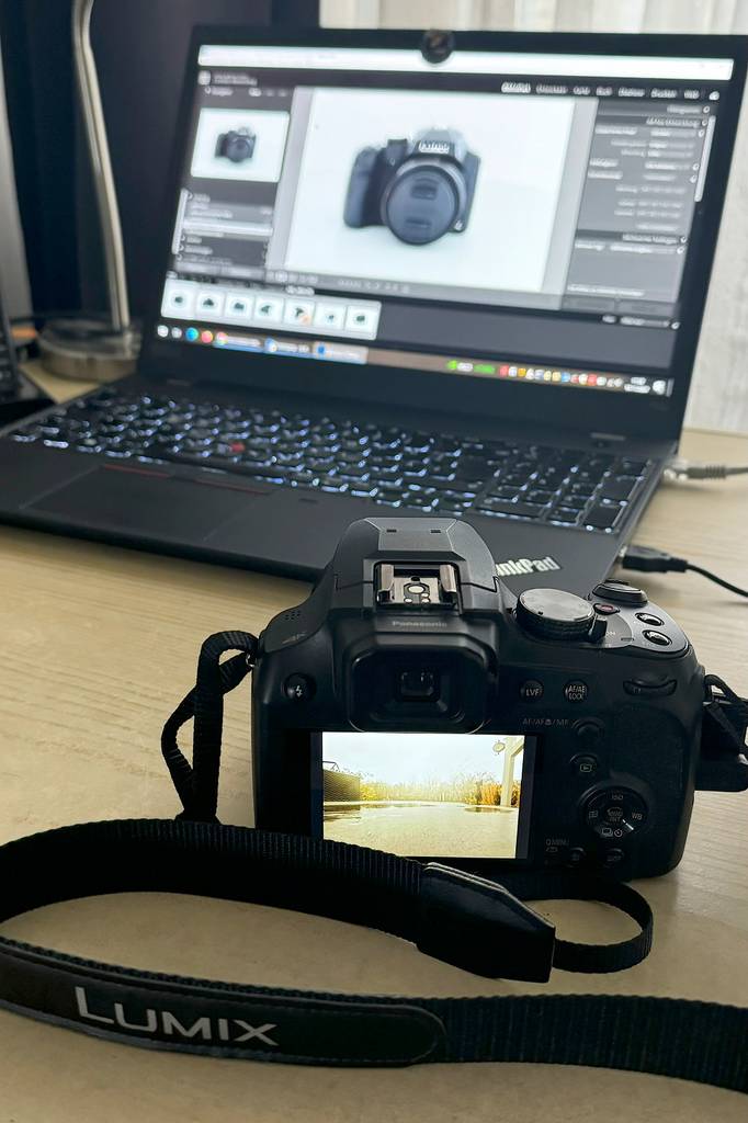 Die getestete Reisezoom-Kamera steht vor einem Laptop, worauf ebenfalls die Kamera zu sehen ist.