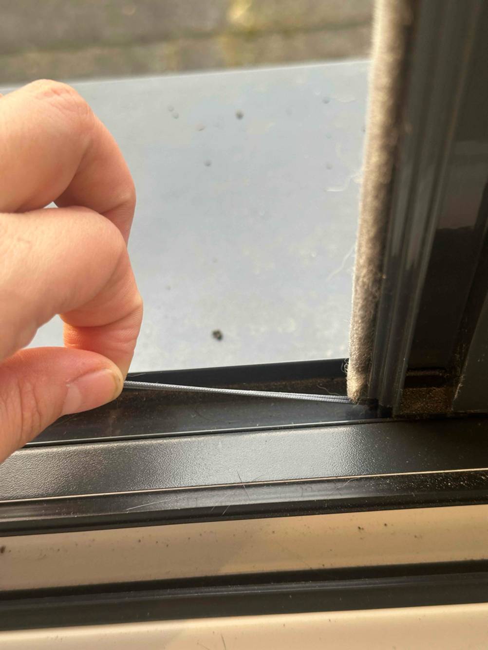 Eine dünne Schnur, das sich am unteren Rahmen einer getesteten Insektenschutzrollo befindet.