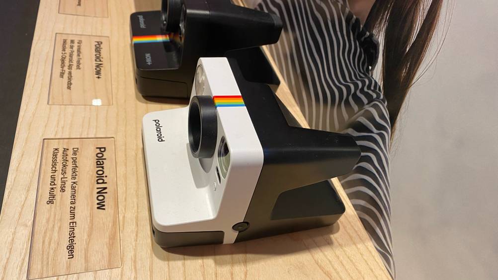 Im Test: Eine Polaroid-Kamera von der Seite neben andereren auf einer Holzfläche.