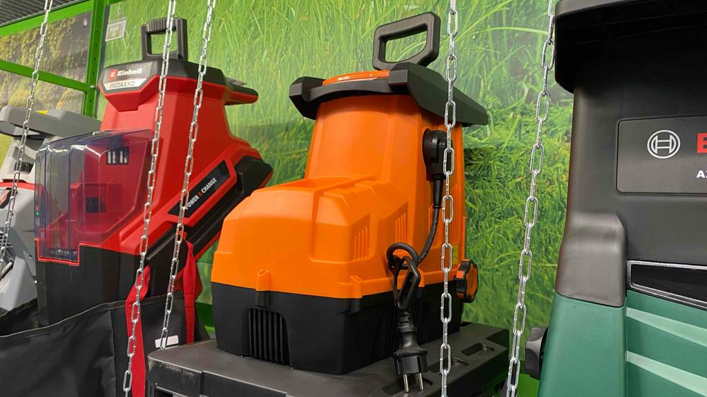 Walzenhäcksler-Test: ein Walzenhäcksler in Orange-schwarz steht in einem Geschäft neben anderen Modellen.