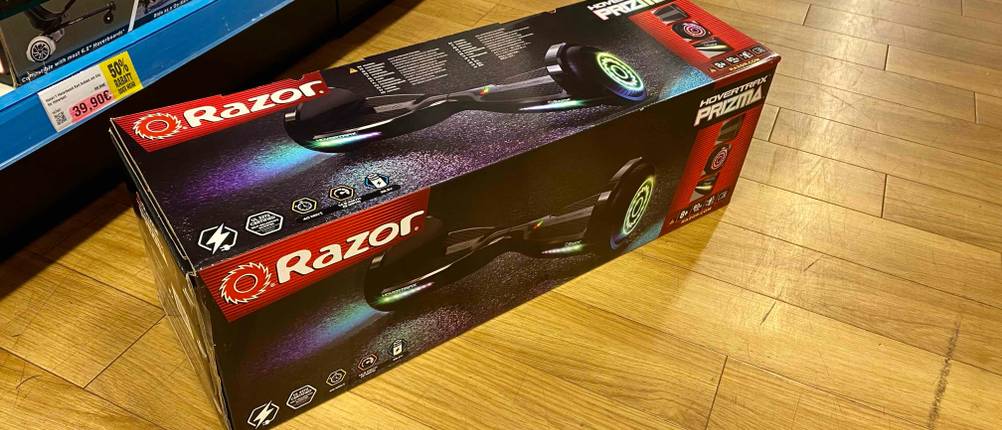 Hoverboard-Test: auf einem Holzboden liegt ein verpacktes Hoverboard der Marke Razor vor einem Regal