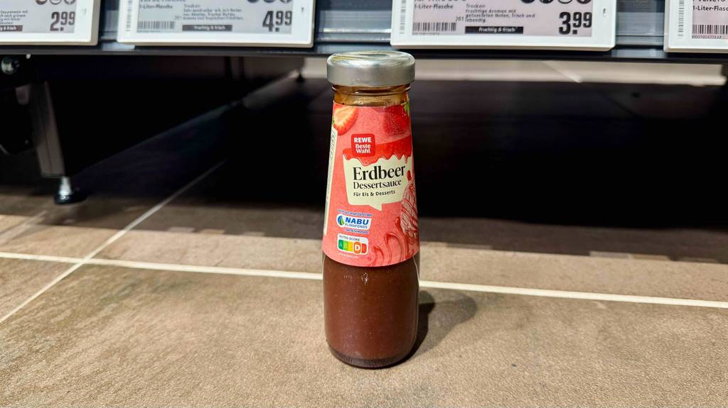 Eine Flasche getesteter Erdbeersauce steht vor einem Regal.