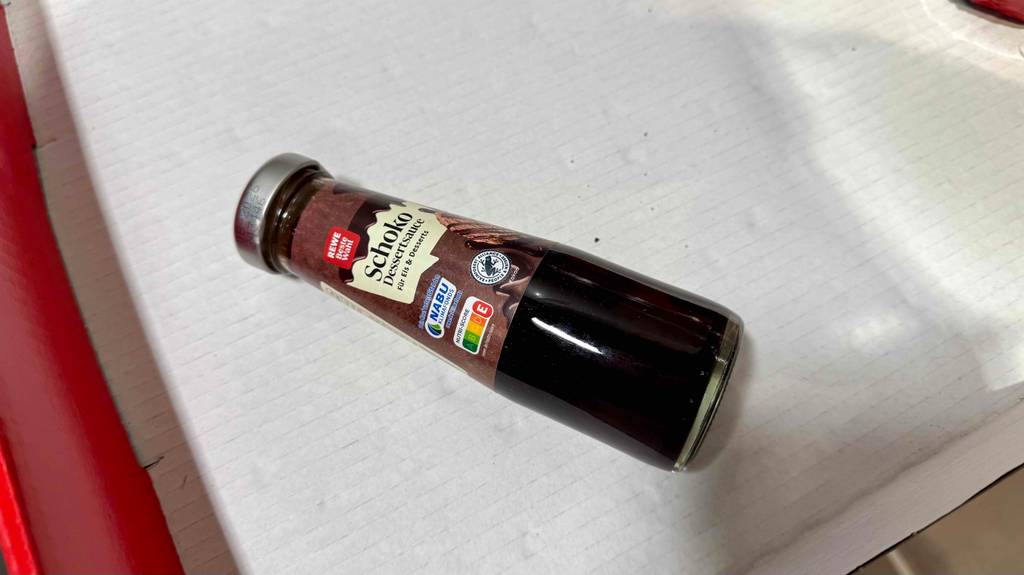 Eine liegende Flasche der getesteten Schokoladensauce mit der Nutriscore-Tabelle darauf ersichtlich.