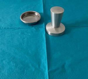 Tamper-Test: Tamper mit dazugehöriger Tamperschale auf einem blauen Untergrund.