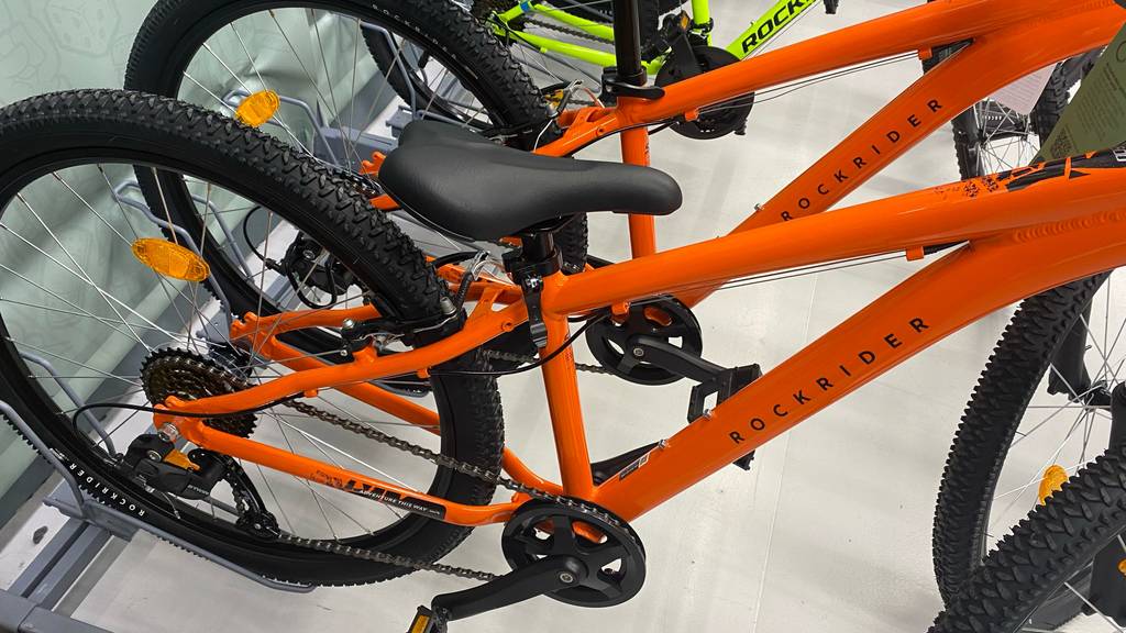 Jugendfahrrad-26-Zoll im Test: oranges Jugendfahrrad steht neben anderen Fahrrädern in einem Geschäft.