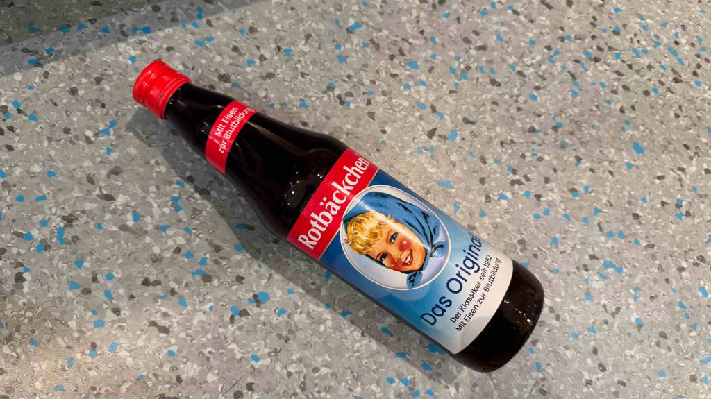 Eine Flasche getesteter Rotbäckchen-Saft liegt auf einem gepunkteten Boden.