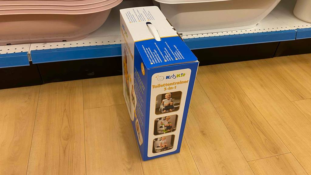 Toilettentrainer getestet: Ein verpackter Toilettentrainer von der Seite vor einem Regal stehend.