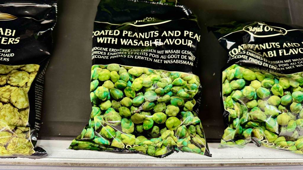 Getestete Wasabi Nüsse in der 300-g-Tüte stehen nebeneinander auf einem weißen Regal.