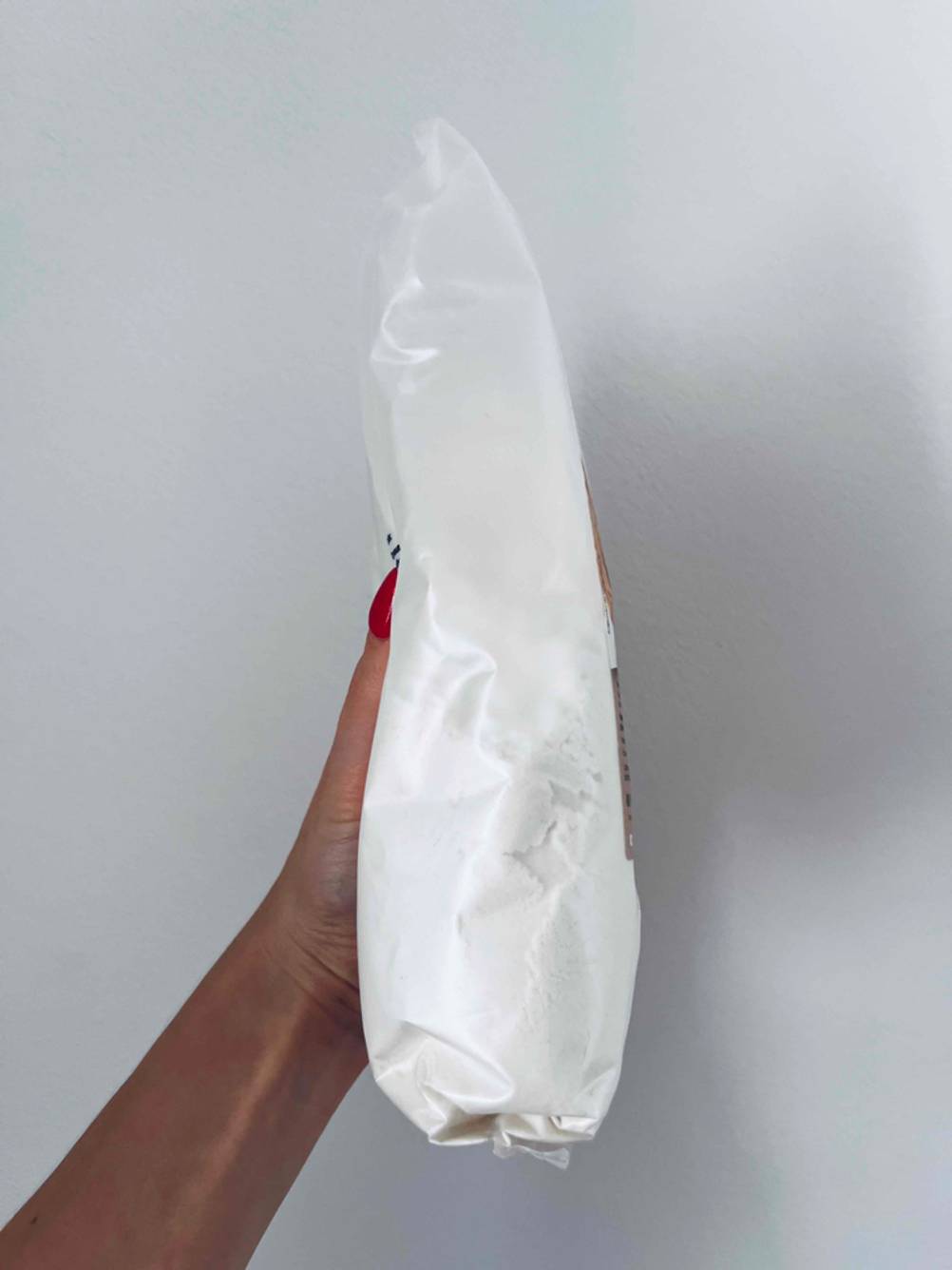 Im Test: Eine Hand hält eine Packung Reismehl seitlich vor eine helle Wand.