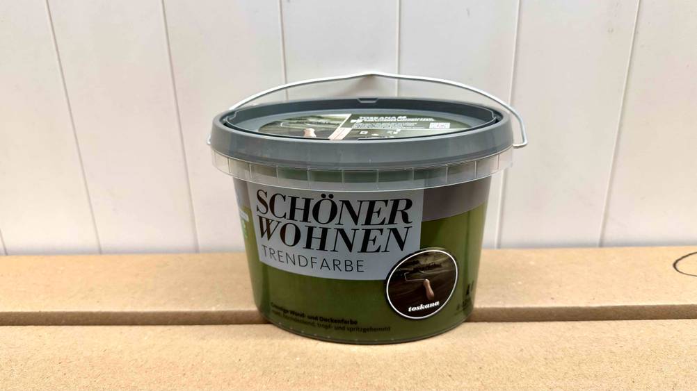 Die getestete grüne Wandfarbe von Schöner Wohnen steht auf Kartons.