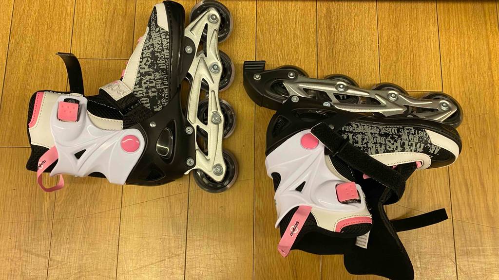 Im Test: Ein Paar Inline-Skates für Kinder liegen quer auf einem Holzboden.