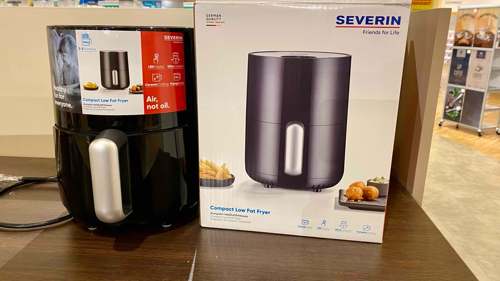 Eine kleine Heißluftfritteuse neben ihrer Originalverpackung im Test.