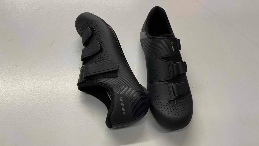 Rennradschuhe-Test: ein Paar liegende Rennradschuhe in Schwarz: mit Sicht auf Klettverschlüsse und Profilsohle.