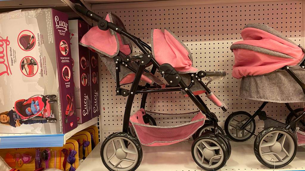 Ein getesteter Zwillingspuppenwagen von der Seite in einem Regal.