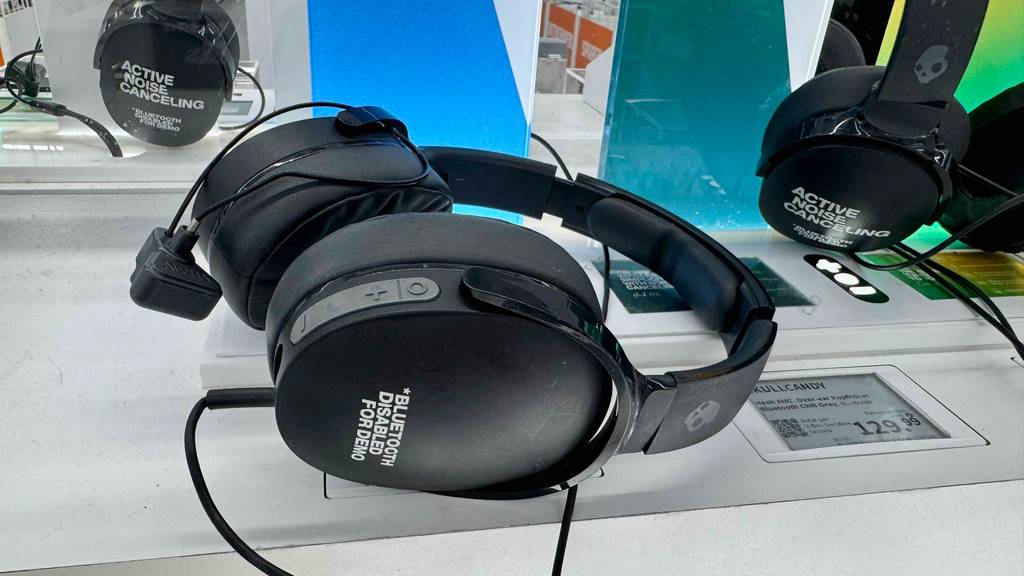 Der schwarze getestete Skullcandy Kopfhörer liegt auf einem Ausstellungstisch im Verkaufsbereich neben seinem Preisschild.