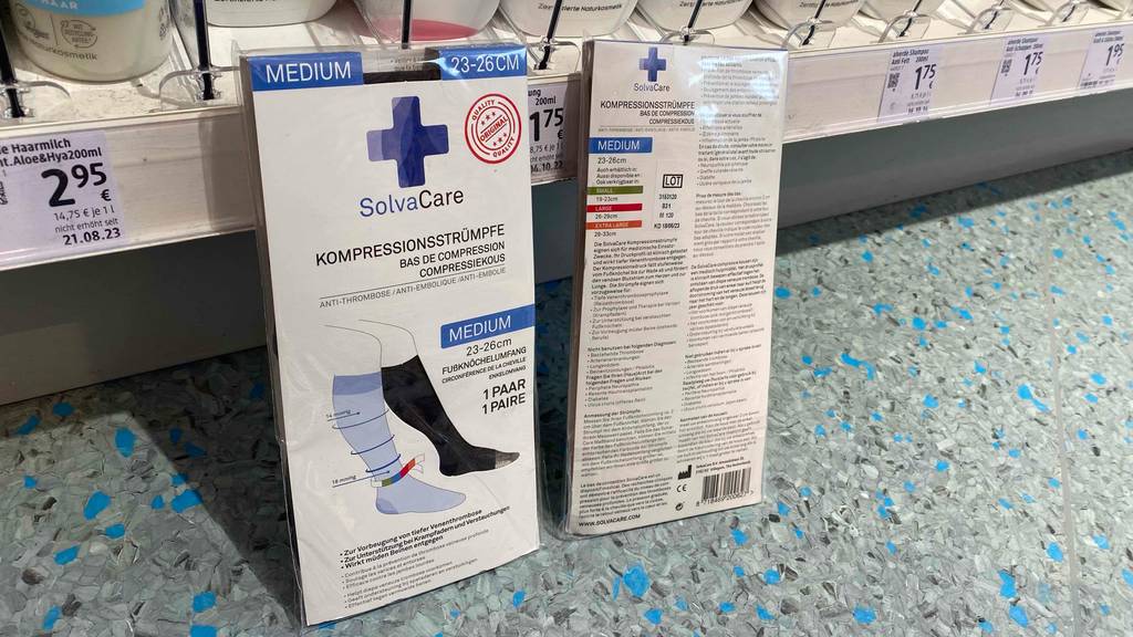 Stützstrümpfe-Test: Eine Packung von vorne eine von hinten lehnen an einem Regalbrett.