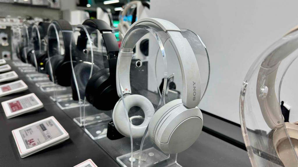 Der weiße Sony-Over-Ear-Kopfhörer im Test hängt neben weiteren Kopfhörern im Ausstellungsbereich eines Geschäftes.
