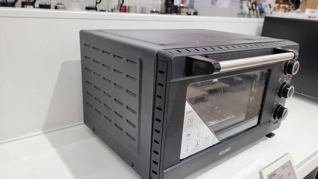 Minibackofen mit Drehspieß-Test: ein Minibackofen mit Drehspieß im geschlossenen Zustand, welcher in einem Regal steht.